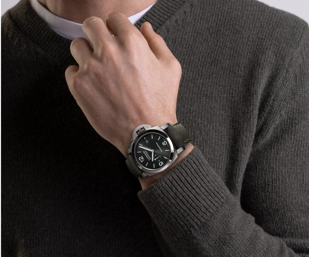 PAM03325 featuring dark green scamosciato calf strap with ecru stitching, brushed Grade 5 titanium trapezoid buckle, and quick-release system visible on both strap and buckle.